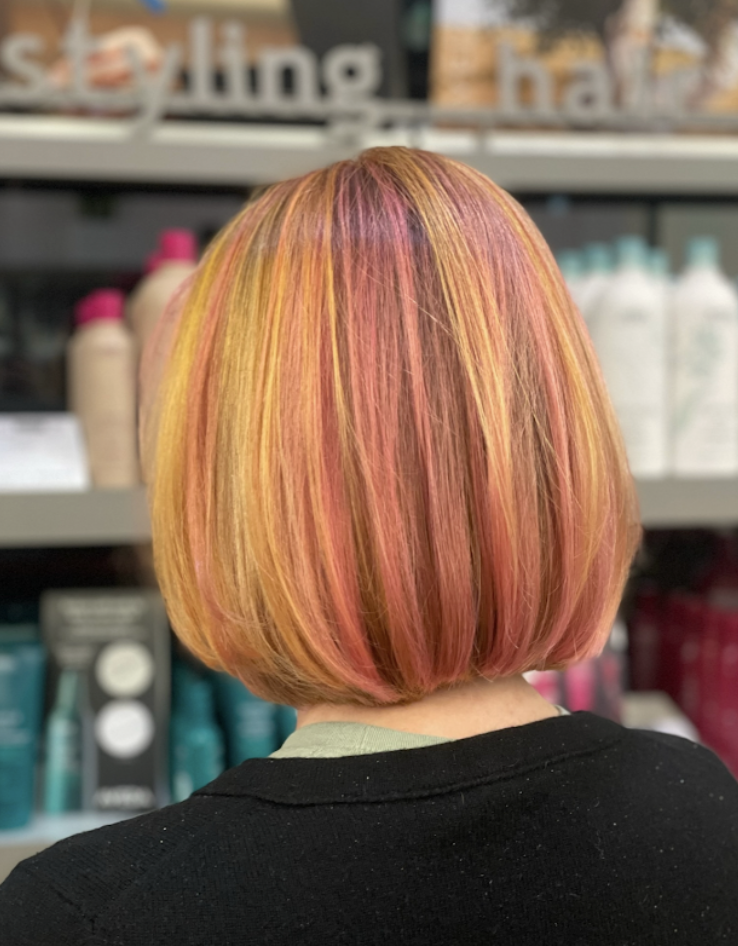Person with a short bob haircut featuring vibrant yellow, orange, and pink colors, viewed from behind in a hair salon. - Atelier Studio, San Jose, CA